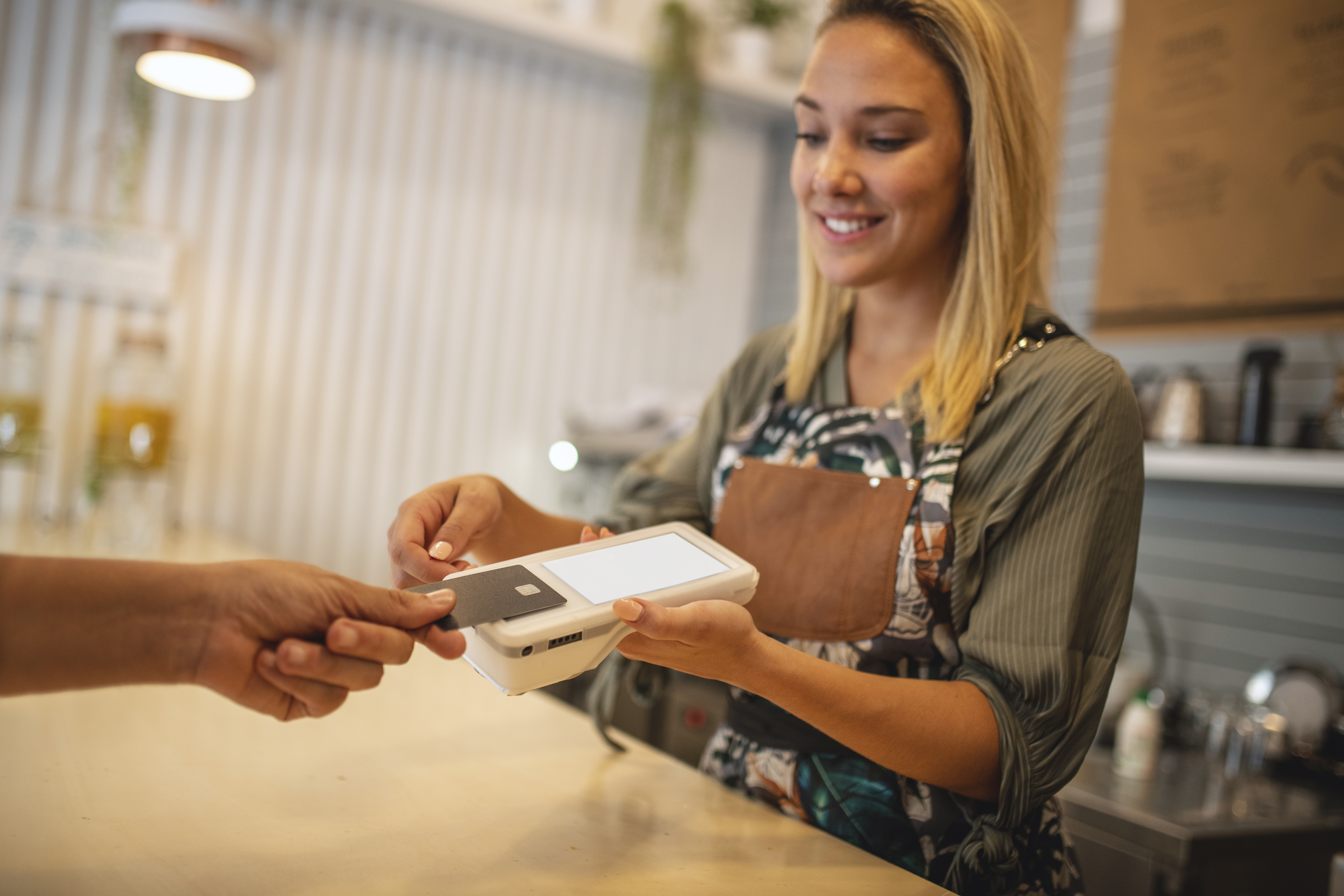 person tapping their credit card on a payment device at a coffee shop